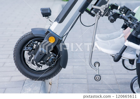 A faceless woman in a wheelchair with an assistive device for manual control. Electric handbike.  120665611