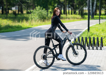 Rear view of Caucasian woman riding bike in park. Rear view of Caucasian woman riding bike in park. 120665613