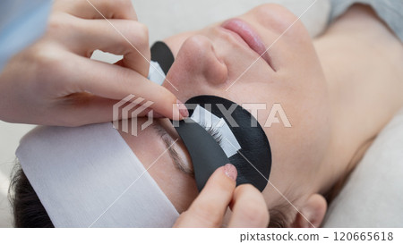 The master applies protective patches that do not let in ultraviolet rays before LED eyelash extensions.  120665618