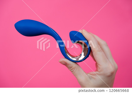 Woman holding blue curved sex toy on pink background. Copy space.  120665668