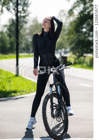 Caucasian woman riding a bike in a park. Vertical photo. Caucasian woman riding a bike in a park. Vertical photo. 120665677
