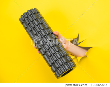 Female hand sticking out with MFR roller yellow paper background. 120665884