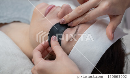 The master applies protective patches that do not let in ultraviolet rays before LED eyelash extensions.  120665902