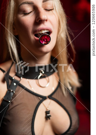 Caucasian woman holds steel anal plug in mouth. Vertical photo. Caucasian woman holds steel anal plug in mouth. Vertical photo. 120665986