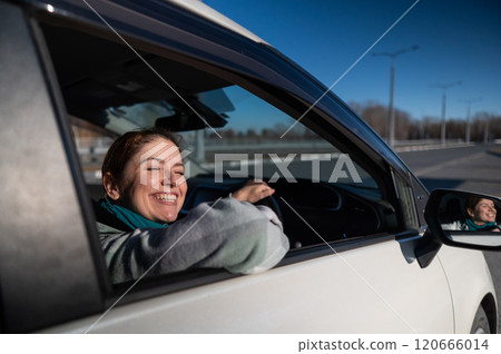 Happy Caucasian woman sitting behind the wheel looking out the window and smiling. Happy Caucasian woman sitting behind the wheel looking out the window and smiling. 120666014