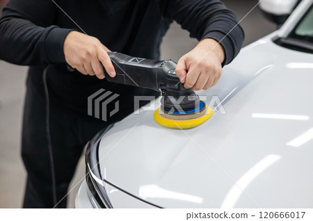 Process of polishing white car hood surface using orbital polishing machine.  Process of polishing white car hood surface using orbital polishing machine.  120666017
