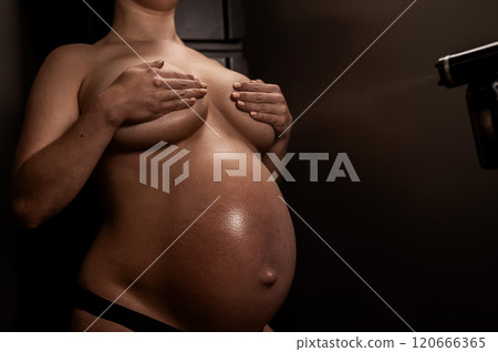 Faceless pregnant woman getting an instant tan. The master applies bronzer with a spray. Faceless pregnant woman getting an instant tan. The master applies bronzer with a spray. 120666365