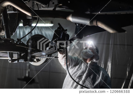 The master sprays an anti-corrosion compound on the bottom of the car. The master sprays an anti-corrosion compound on the bottom of the car. 120666388