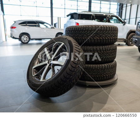 New wheels with studded tires against the background of new cars.  120666550