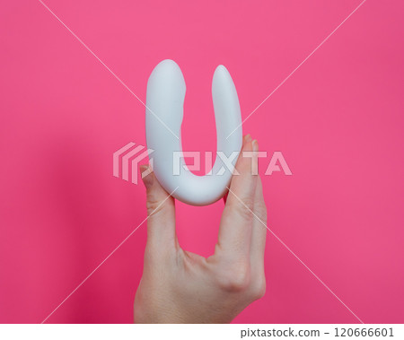 Woman holding white curved sex toy on pink background.  120666601