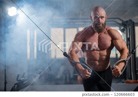 Bald Caucasian bodybuilder training chest using cable crossover in gym. Bald Caucasian bodybuilder training chest using cable crossover in gym. 120666603