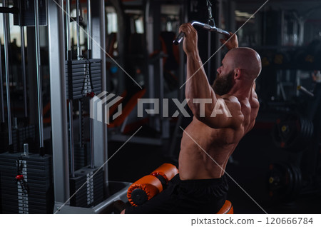 Caucasian man doing lat pull-downs on a machine.  120666784