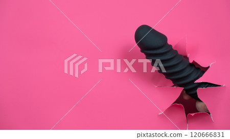 Black ribbed dildo sticking out of hole on pink background.  120666831