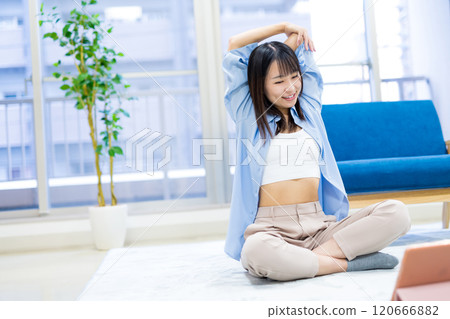 年輕女性在家鍛煉，同時在平板電腦上觀看 YouTube 影片 — 瑜伽、伸展運動、飲食、健康 120666882