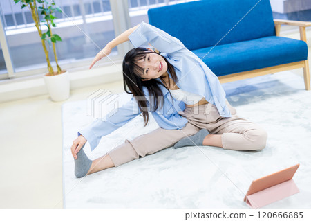 年輕女性在家鍛煉，同時在平板電腦上觀看 YouTube 影片 — 瑜伽、伸展運動、飲食、健康 120666885