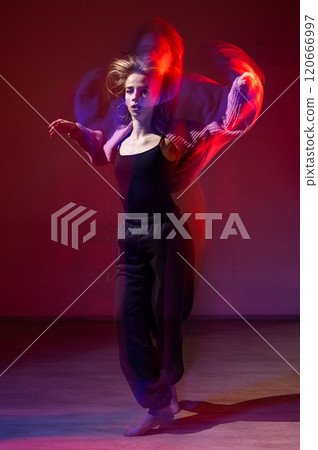 A young woman dances contemporary dances in blue and red light. Long exposure. Vertical photo. A young woman dances contemporary dances in blue and red light. Long exposure. Vertical photo. 120666997