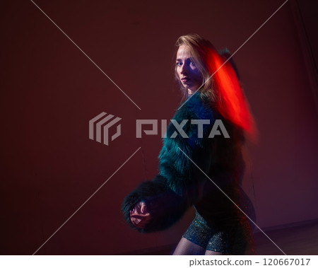 A young woman dances contemporary dances in blue and red light. Long exposure photo.  120667017