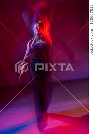 A young woman dances contemporary dances in blue and red light. Long exposure. Vertical photo.  120667032
