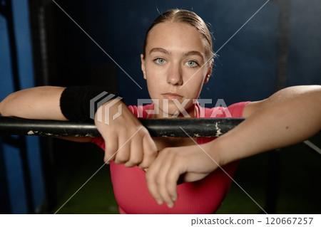 Portrait of young confident woman in good physical shape posing with hands on horizontal bar captured during daily training in gym, copy space 120667257