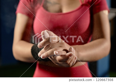 Close up on hands of unrecognizable fit woman chalking hands rubbing magnesia into palms for safe gymnastics training in gym, copy space 120667308