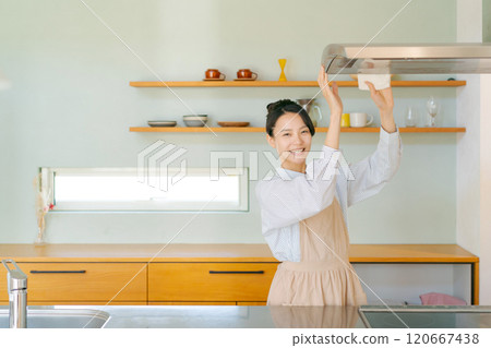 Woman cleaning the ventilation fan in the kitchen 120667438