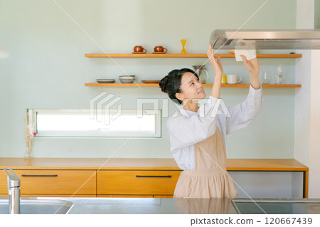 Woman cleaning the ventilation fan in the kitchen Woman cleaning the ventilation fan in the kitchen 120667439