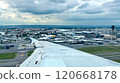 Descending airplane wing over toulouse blagnac airport and aeroconstellation museum against a cloudy sky 120668178