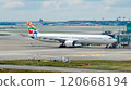 White passenger plane taxiing toward gate on sunny airport runway 120668194