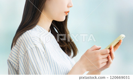 Woman/businesswoman thinking while looking at her smartphone Woman/businesswoman thinking while looking at her smartphone 120669031
