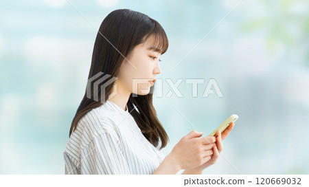 Woman/businesswoman thinking while looking at her smartphone Woman/businesswoman thinking while looking at her smartphone 120669032