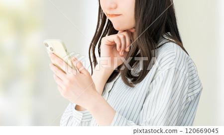 一位女商人看著她的智慧型手機並思考 120669045