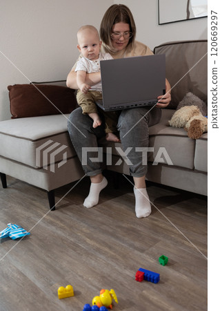 A Parent Juggling Working from Home while Comfortably Sitting with a Baby on Lap 120669297