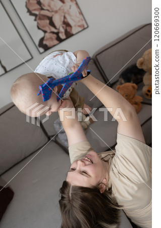 A joyful interaction between a mother and her adorable baby in their cozy living room 120669300