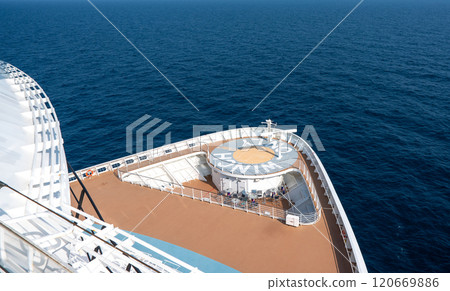 Aerial view of cruise ship, showcasing top deck with swimming pools, sun loungers, sailing in clear blue ocean waters 120669886