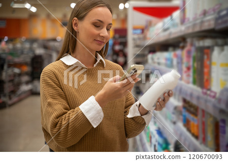 Woman scans cosmetics products while shopping in supermarket aisle during daytime Woman scans cosmetics products while shopping in supermarket aisle during daytime 120670093