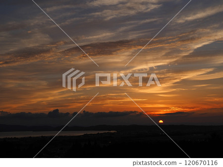 雲層後的夕陽和橙色的雲彩在深藍色的天空的映襯下顯得令人印象深刻且美麗。 雲層後的夕陽和橙色的雲彩在深藍色的天空的映襯下顯得令人印象深刻且美麗。 120670116