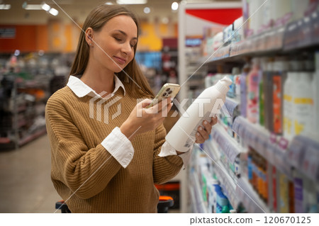 Woman scans cosmetics products in a store to check ingredients and information while shopping for beauty items 120670125