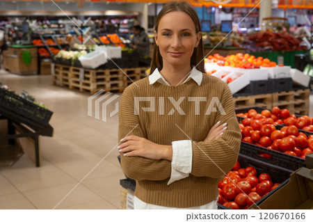 Woman standing confidently in grocery store with fresh produce on display 120670166