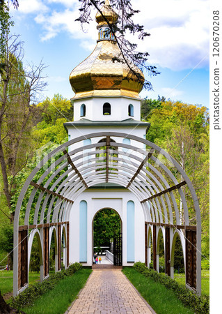 Majestic archway leading to a golden-domed structure in a vibrant green park 120670208