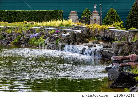 Tranquil waters cascade gently through a lush garden paradise in summer Tranquil waters cascade gently through a lush garden paradise in summer 120670211