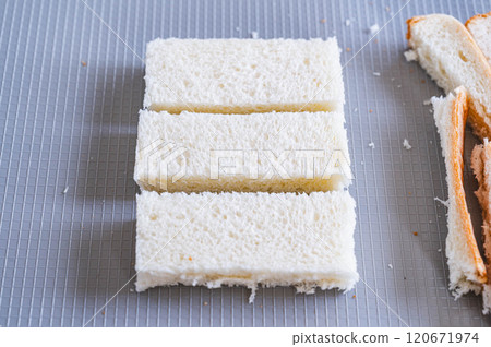 Remove the crusts from the bread and cut it into thirds. Remove the crusts from the bread and cut it into thirds. 120671974