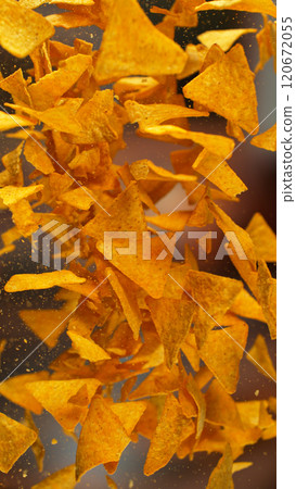 Freeze motion of flying fried tortilla nachos chips on gradient yellow background 120672055