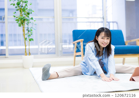 Young woman exercising at home while watching YouTube videos on tablet Yoga Stretching Diet Health 120672116