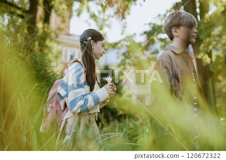 Side view medium shot of teen boy and girl walking along path in local botanical garden 120672322