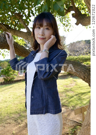 A young woman wearing a white dress posing in a park A young woman wearing a white dress posing in a park 120672822