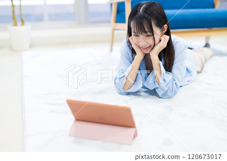 一名年輕女子在假期期間靠著下巴在平板電腦上觀看 YouTube 影片。 一名年輕女子在假期期間靠著下巴在平板電腦上觀看 YouTube 影片。 120673017