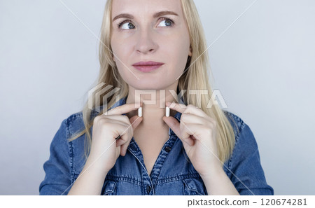 Dietary supplement or medicine for treating thyroid disease. Woman holding capsules near her neck. Maintaining Thyroid Health 120674281