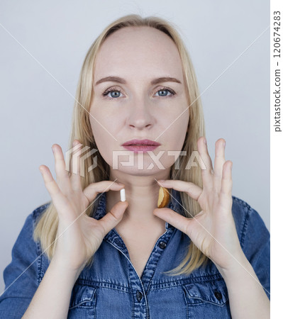 Woman considers what is better to eat to replenish selenium - a dietary supplement or a Brazil nut. Prevention of thyroid diseases 120674283