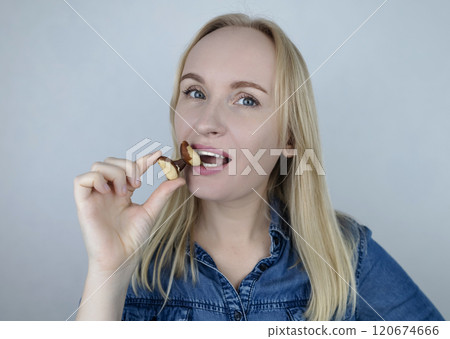 Prevention of thyroid disease. Woman holding a brazil nut in the shape of a thyroid gland. Nut rich in selenium 120674666