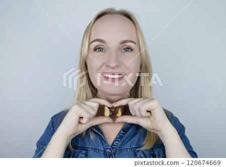 Prevention of thyroid disease. Woman holding a brazil nut in the shape of a thyroid gland. Nut rich in selenium 120674669